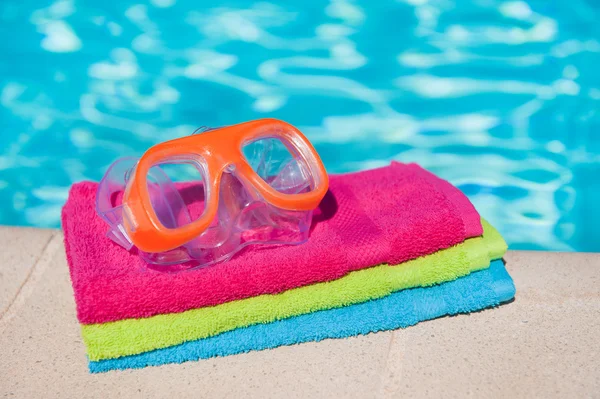 Handdukar och skyddsglasögon nära poolen — Stockfoto