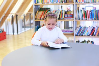 Child reading in library clipart