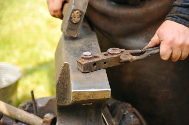 Blacksmith hammering hot steel on anvil clipart