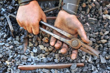 Detail of dirty hands holding pliers - blacksmith clipart