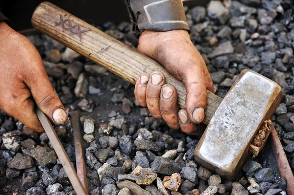 Detalle de manos sucias sosteniendo martillo y varilla - herrero — Foto de Stock