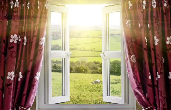 Открытое окно с видом на сельскую местность и солнечным светом — стоковое фото