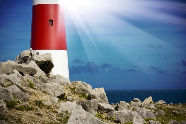 Lighthouse on rocks with light beams — Stock Photo, Image