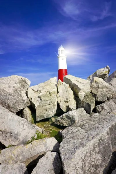 Faro su rocce con fasci di luce — Foto Stock