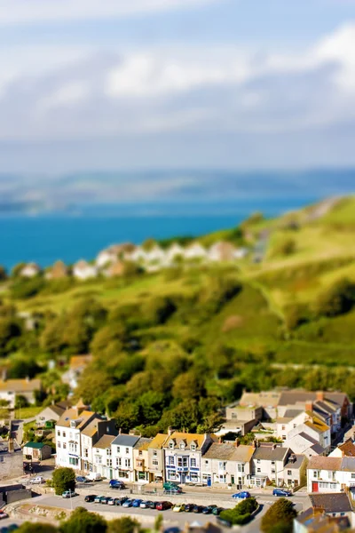 Fake toy village view over rolling hills and sea in the distance — Stock Photo, Image