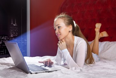 genç kadın yatakta dizüstü bilgisayar ile