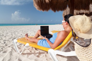 Woman with laptop on the beach clipart