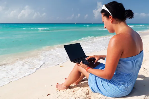Vrouw met laptop op het strand — Stockfoto