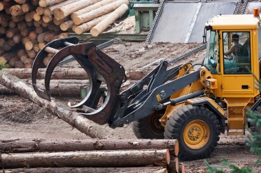 Skidder hauling logs at sawmill. clipart