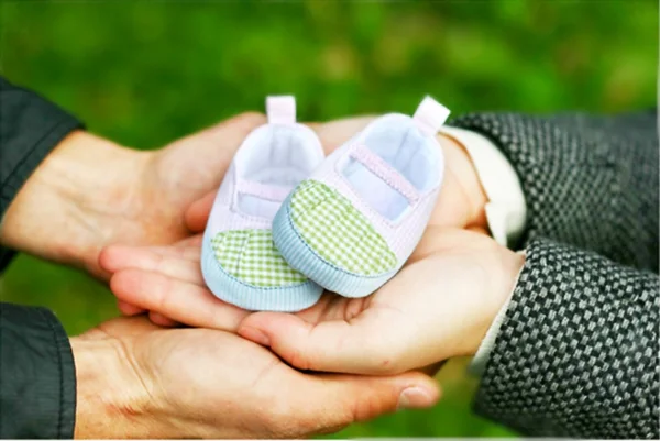 Pregnant couple holding a little boot in their arms. Close-up. — Stock Photo, Image