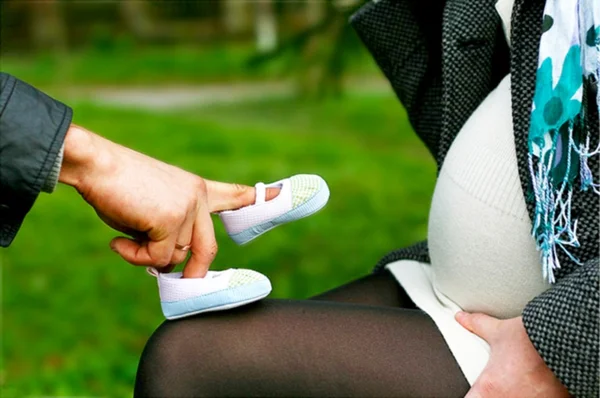 Söt man leker med Babyskor på sin gravida fru — Stockfoto