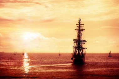Pirate ship sailing in the sunset clipart