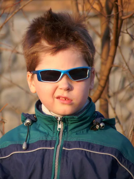 Un ragazzo con gli occhiali con una smorfia sul viso — Foto Stock