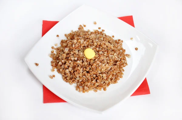 Аппетитная крошечная гречка с маслом на белом фоне — стоковое фото