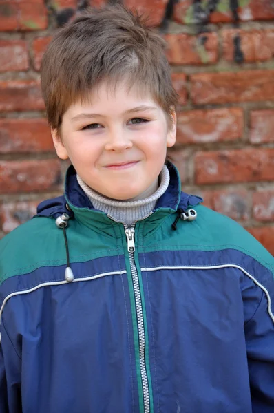 Porträtt av en leende pojke i bakgrunden av en gammal tegelvägg — Stockfoto