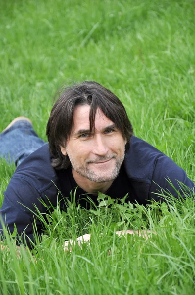 Человек, лежащий на зеленой траве — стоковое фото