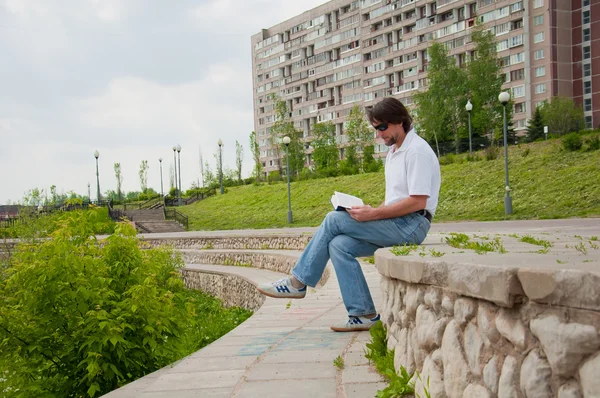Un uomo legge un libro nel parco cittadino — Foto Stock
