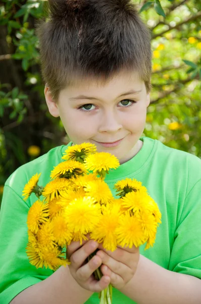 Um menino com um buquê de dentes-de-leão — Fotografia de Stock