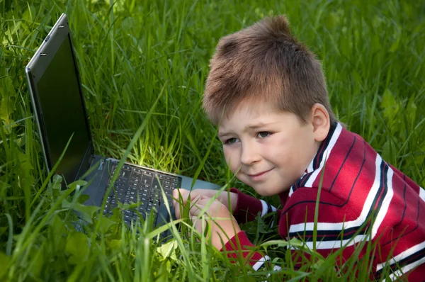 躺在草地上的膝上型计算机的男孩 — 图库照片