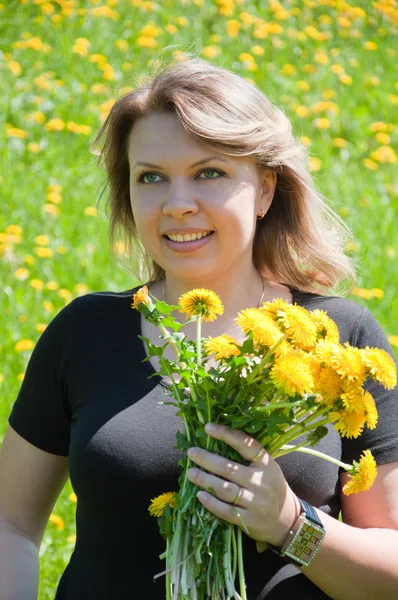 Portrait of a young girl on the lawn with a bouquet of dandelions — Stock Photo, Image