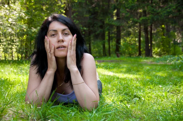 Krásná žena středního věku, ležící na trávě — Stock fotografie