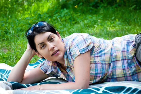 Bela mulher de meia-idade deitada na grama — Fotografia de Stock