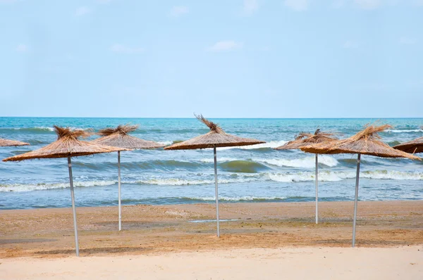 Słomiane parasole na plaży na tle morza — Zdjęcie stockowe