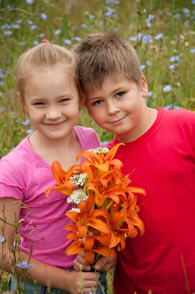 Menino e menina com um buquê de lírios laranja — Fotografia de Stock