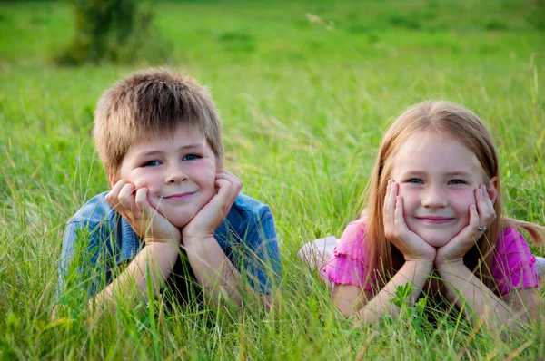 Lustige Jungen und Mädchen liegen auf Gras — Stockfoto