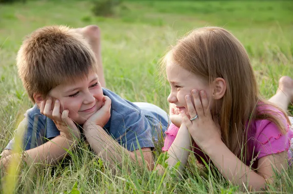 Zabawny chłopak i dziewczyna leżąc na trawie — Zdjęcie stockowe