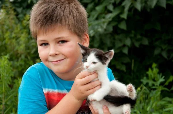 Un chico y divertido gatito en sus brazos — Foto de Stock