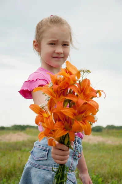Flicka med en bukett av orange liljor — Stockfoto