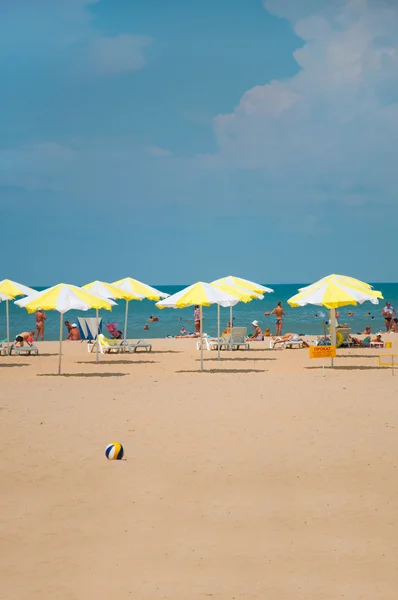 Sandy beach with parasols by the sea — Stock Photo, Image