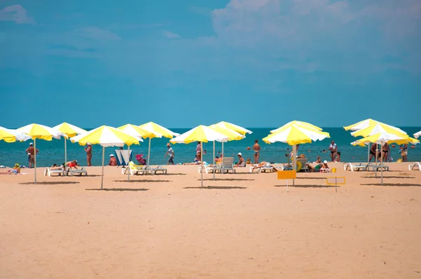 Sandy beach with parasols by the sea — Stock Photo, Image