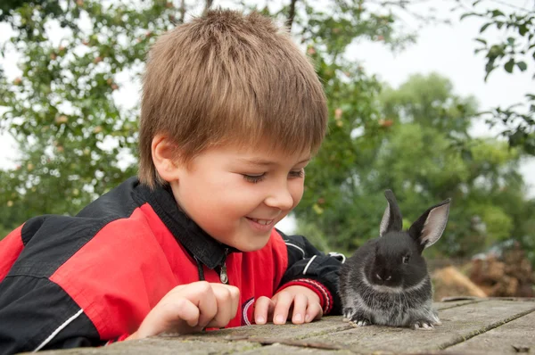 A boy with a rabbit in the garden at the cottage — Stock Photo, Image