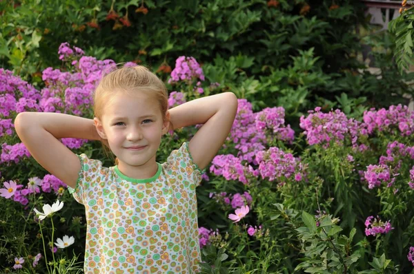 Menina bonita de pé nas flores — Fotografia de Stock