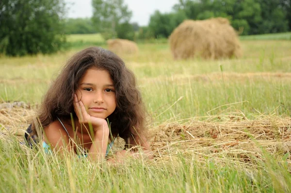 Mooi meisje in een veld op een achtergrond van stro — Stockfoto