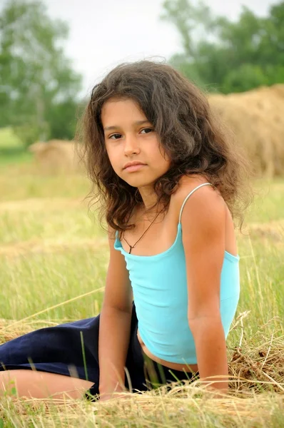 Красивая девушка в поле на фоне соломы — стоковое фото