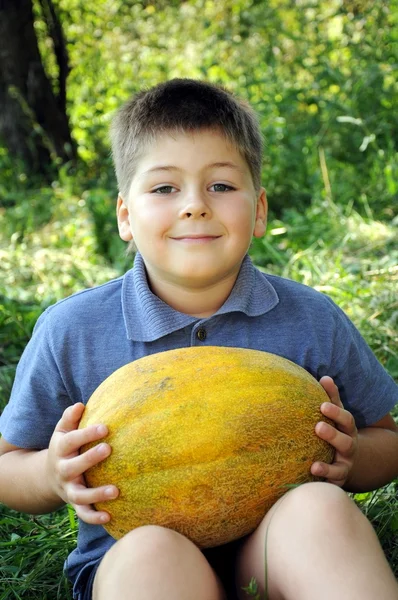 En pojke med en stor melon i hans händer — Stockfoto