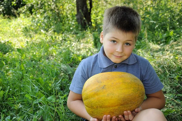 Een jongen met een grote meloen in zijn handen — Stockfoto