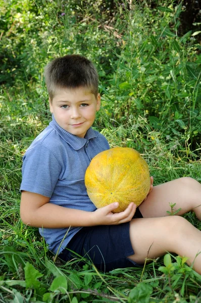 Een jongen met een grote meloen in zijn handen — Stockfoto
