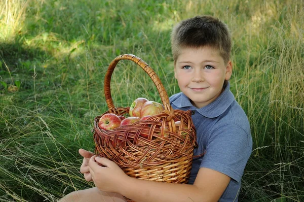 Ein Kind mit einem Korb voller roter Äpfel — Stockfoto