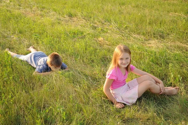 男の子と女の子の牧草地で休んで — ストック写真