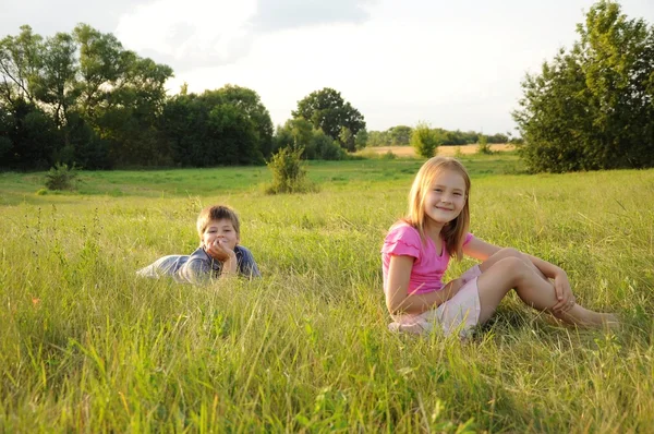 男の子と女の子の牧草地で休んで — ストック写真