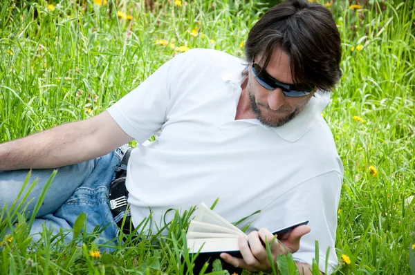 Um homem lê um livro no parque — Fotografia de Stock