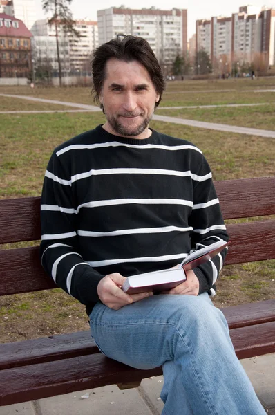 Homme avec livre assis sur un banc — Photo
