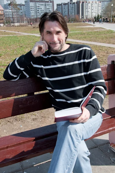Uomo con libro seduto su una panchina — Foto Stock