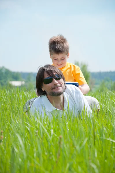 Apa és fia pihentető, zöld fű — Stock Fotó