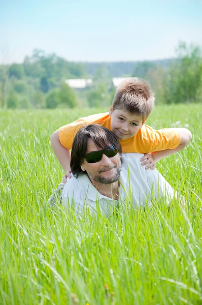 Dad and son relaxing on green grass — Stock Photo, Image