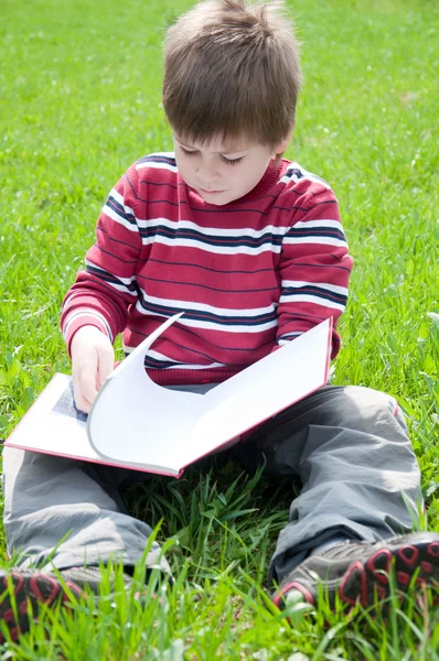 A boy reads a book in the park — Stock Photo, Image